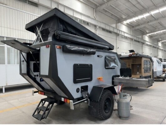 Camper with the pop-up roof raised and steps extended